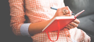 Girl writing in red journal.